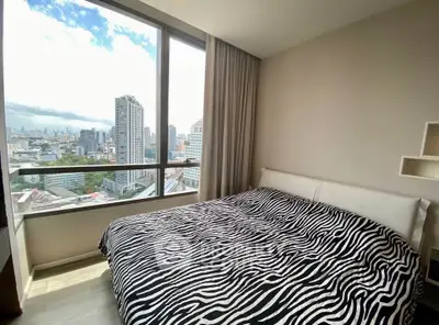 Modern bedroom with large window offering stunning city view and stylish zebra print bedding.