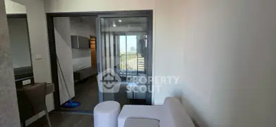 Modern living room with glass sliding doors and city view, featuring sleek furniture and contemporary design.