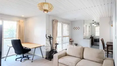 Charming open-plan living room with modern decor and natural light, featuring a cozy workspace and exercise area.