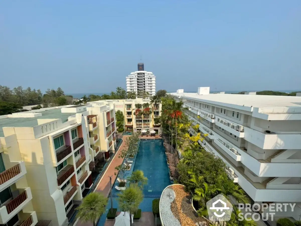 Stunning aerial view of luxury apartment complex with central pool and lush greenery.