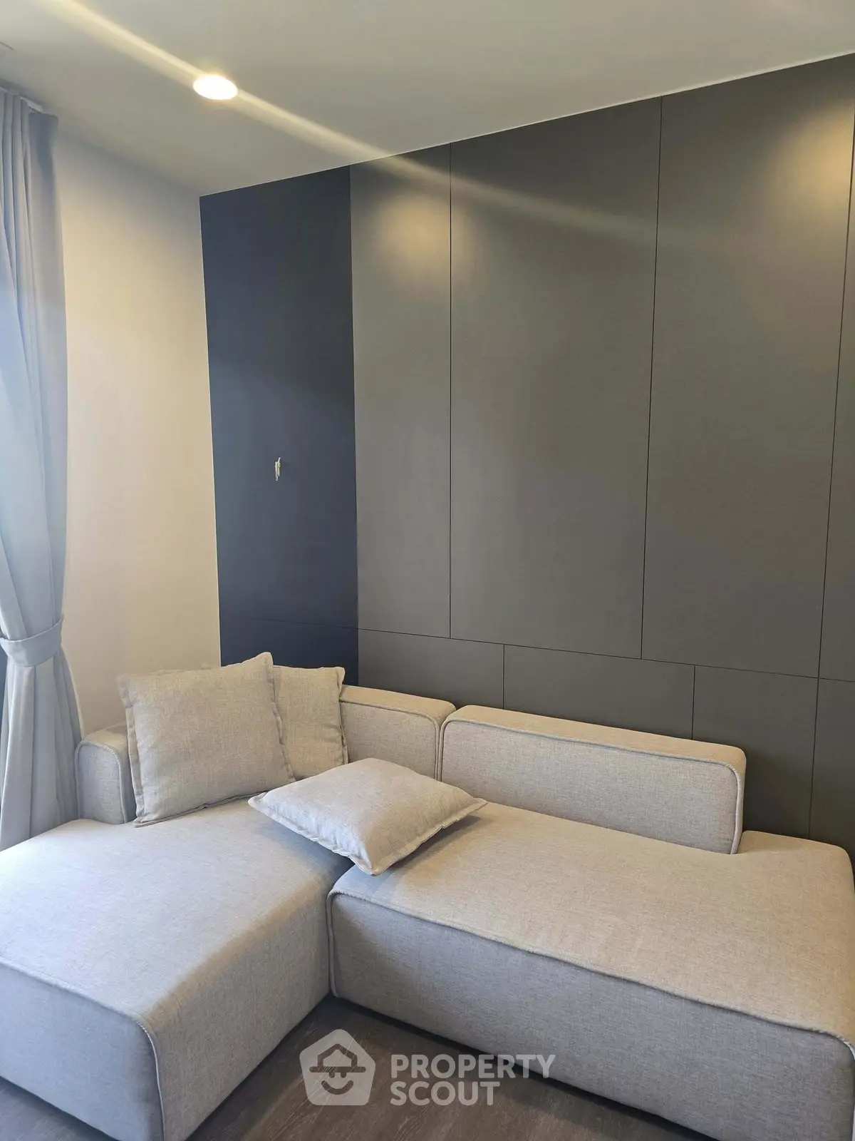 Modern living room with sleek gray sectional sofa and elegant wall paneling