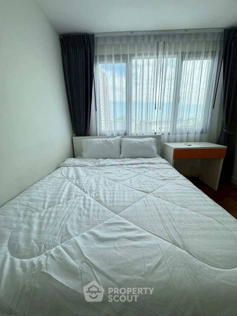 Cozy bedroom with large window and modern furnishings in urban apartment.