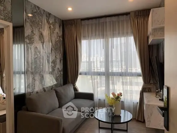 Cozy living room with modern decor and large window offering natural light.