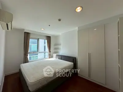 Bright and spacious bedroom with large window and modern furnishings in a contemporary apartment.