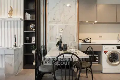 Modern kitchen with dining area and built-in washing machine, featuring sleek cabinetry and marble accents.