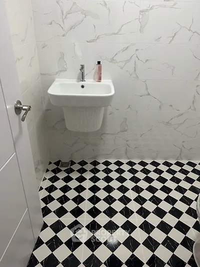 Modern bathroom with stylish black and white checkered floor tiles and elegant wall tiles.