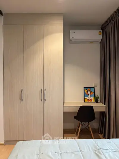 Modern bedroom with built-in wardrobe and cozy study nook, featuring sleek air conditioning unit.