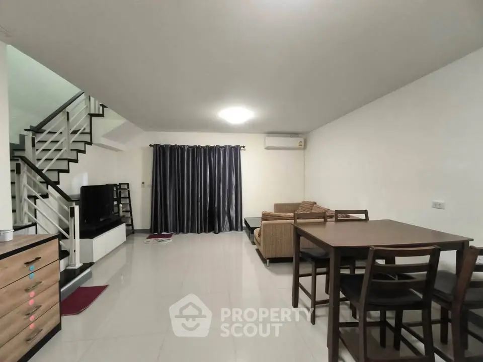 Spacious living room with modern furniture and sleek staircase in a contemporary home.
