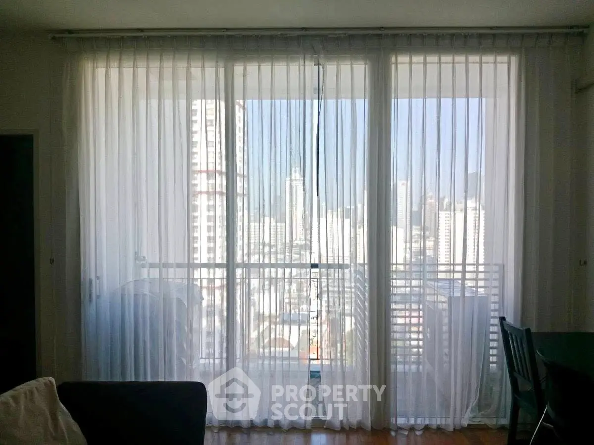 Spacious living room with floor-to-ceiling windows offering stunning city views.