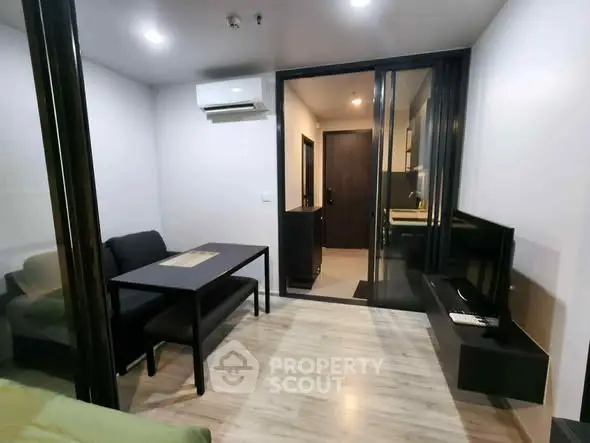 Modern compact living room with sleek furniture and open kitchen layout.