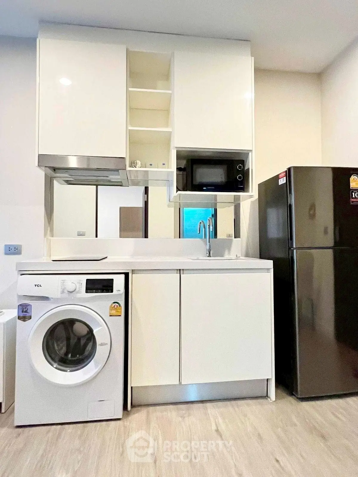 Modern kitchen with sleek appliances and washing machine in compact layout
