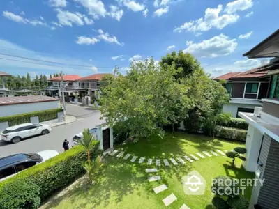 Charming suburban garden with lush greenery and modern houses under a clear blue sky.