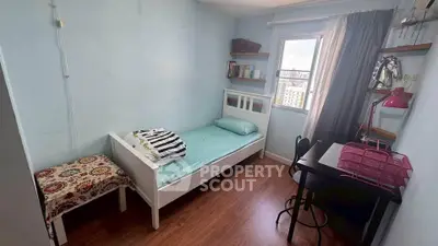 Cozy bedroom with single bed, desk, and city view window, perfect for a student or young professional.