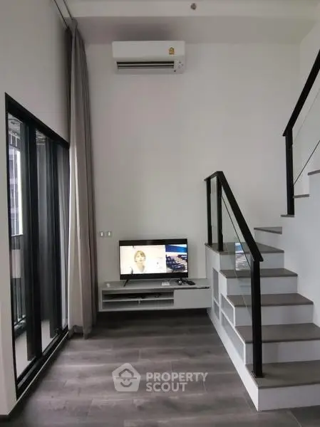 Modern duplex living room with sleek staircase and large window