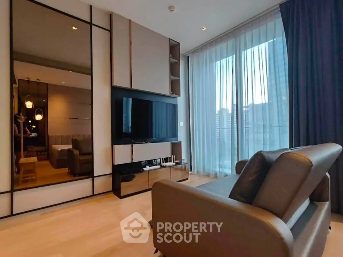 Modern living room with sleek design and city view, featuring a large TV and comfortable seating.