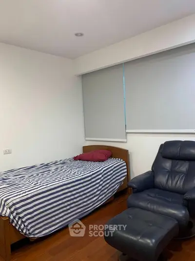 Cozy bedroom with single bed and comfortable recliner, perfect for relaxation.