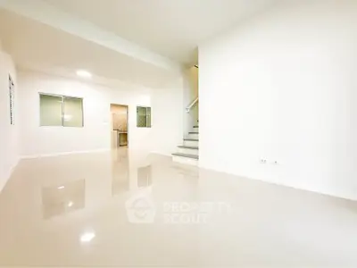 Spacious modern living room with glossy tiled floors and staircase