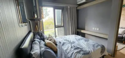 Cozy bedroom with modern decor and large window offering natural light and garden view.