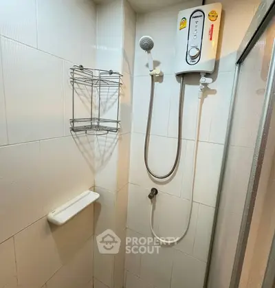 Compact bathroom shower area with electric water heater and wall-mounted storage.
