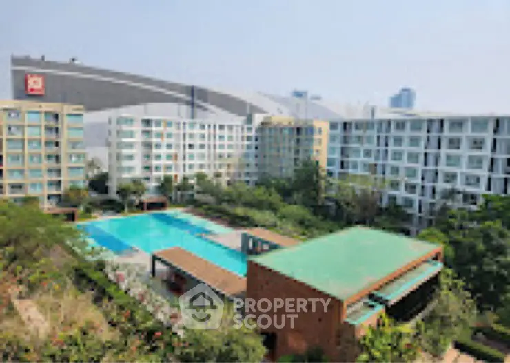 Stunning aerial view of modern apartment complex with large pool and lush greenery.
