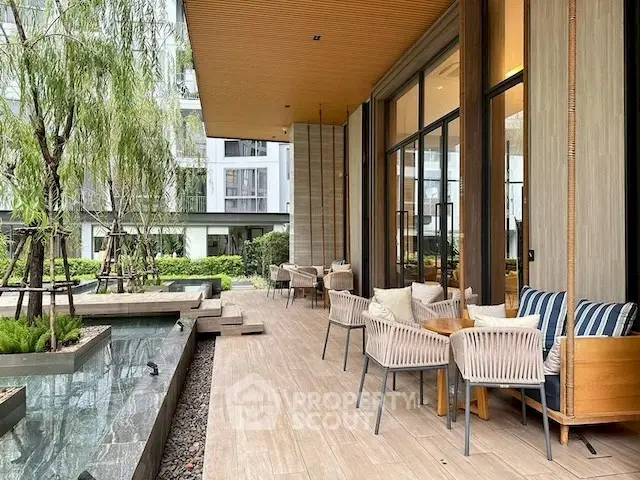 Luxurious outdoor patio with elegant seating and serene garden view in modern residential complex.