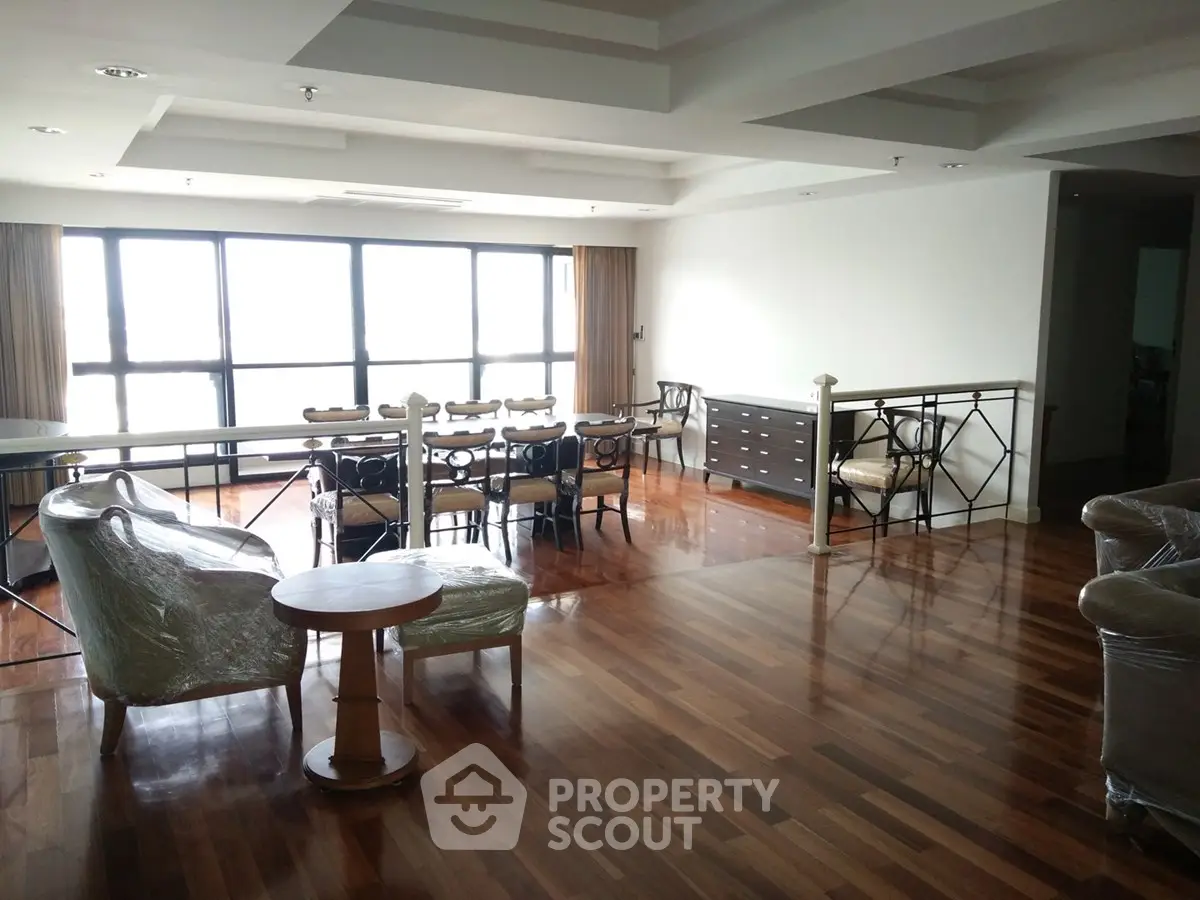 Spacious living room with elegant wooden flooring and large windows offering natural light.