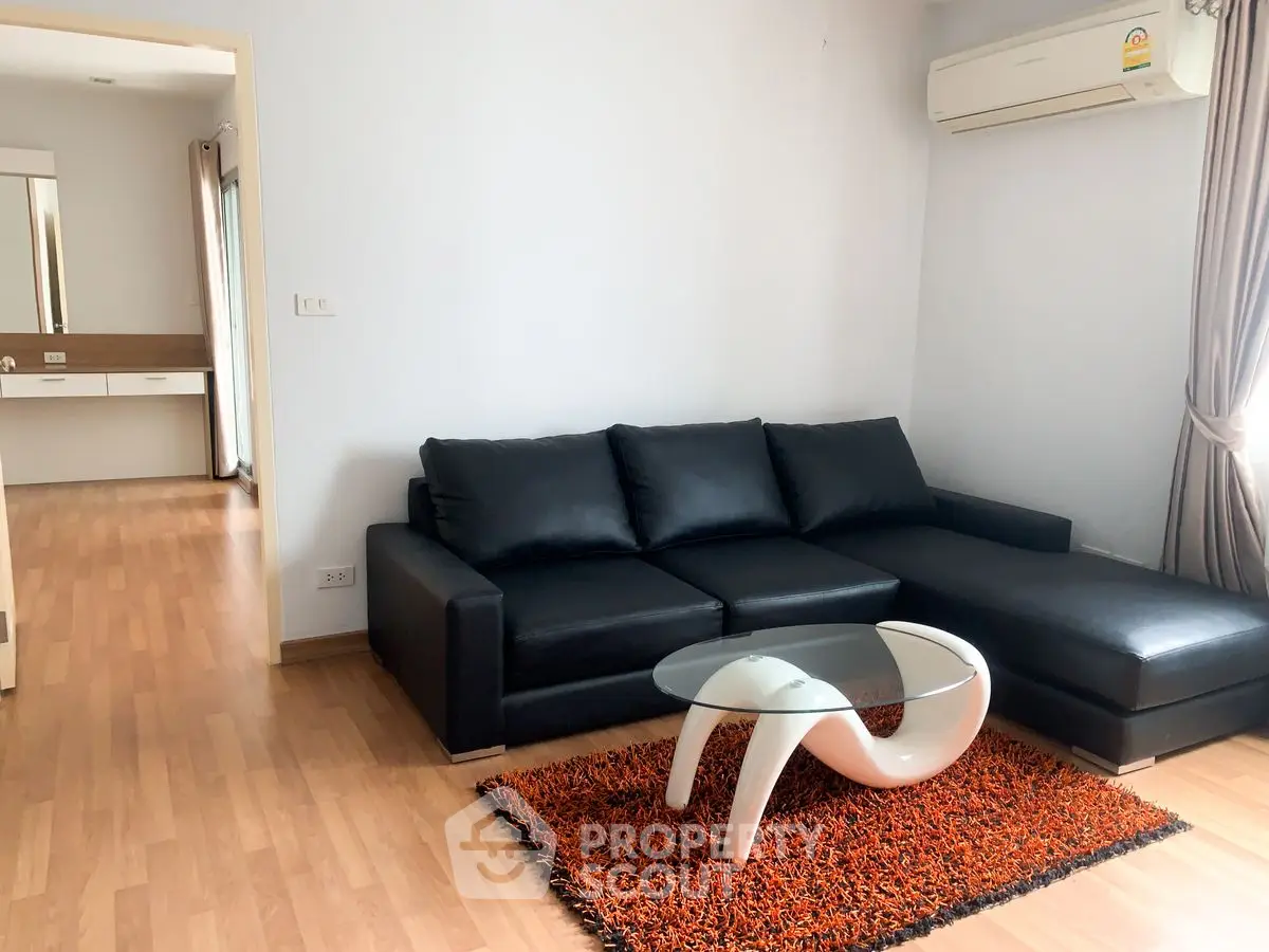 Modern living room with sleek black sofa and stylish coffee table on wooden flooring.
