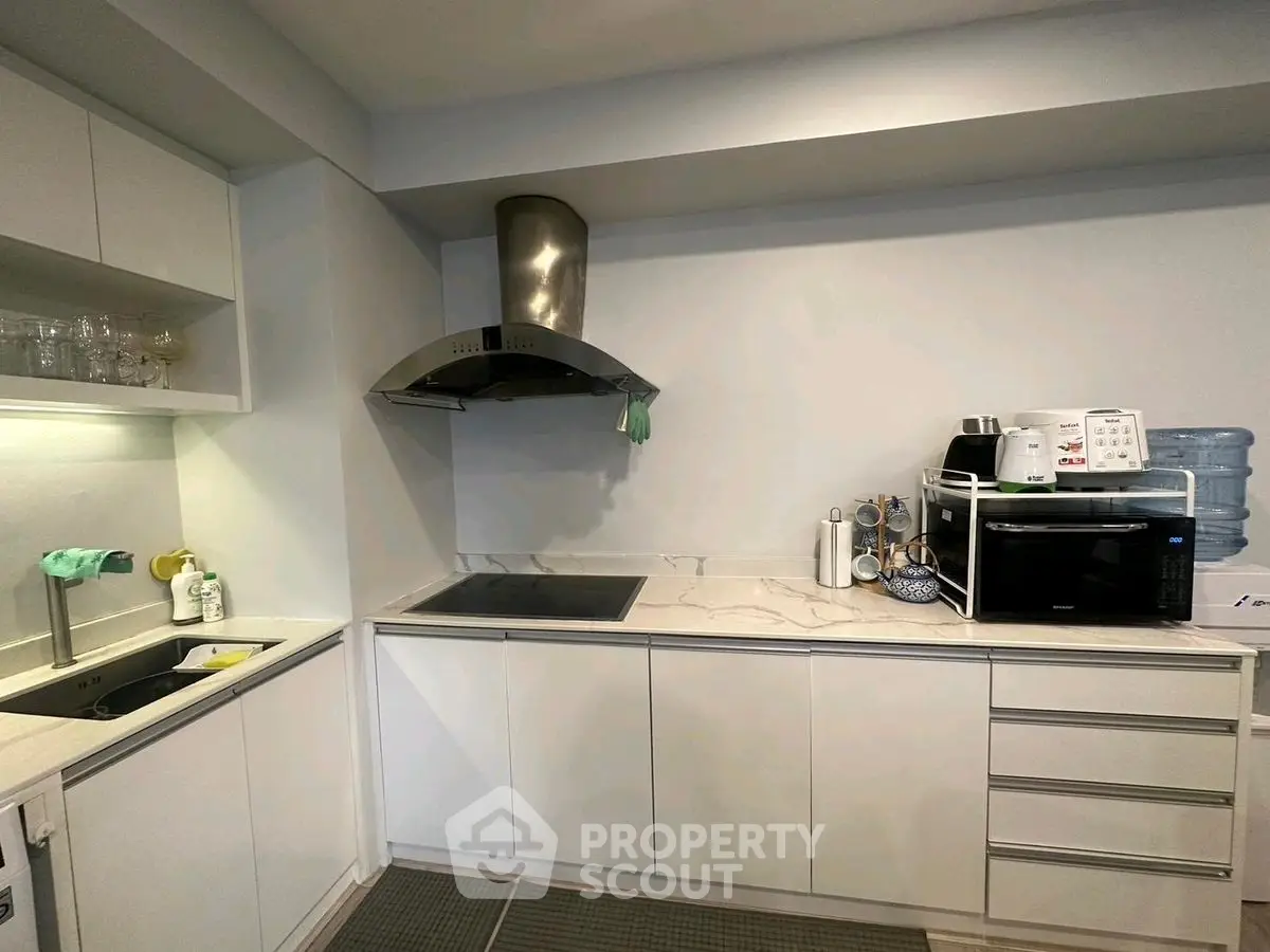 Modern kitchen with sleek cabinets and appliances, featuring a stovetop and microwave for efficient cooking.