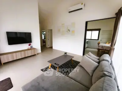 Modern living room with sleek furniture and wall-mounted TV, open layout design.