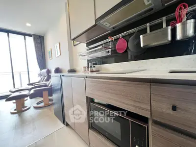 Modern kitchen with sleek cabinetry and cozy living area featuring large windows and stylish seating.