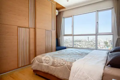 Modern bedroom with large window offering stunning city view and stylish wooden wardrobe.