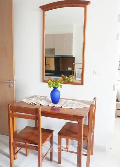 Charming dining nook with wooden table and chairs, accented by a vibrant blue vase and mirror.