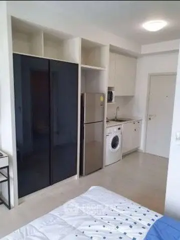 Modern studio apartment with compact kitchen and appliances, ideal for urban living.