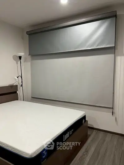 Modern bedroom with sleek blinds and minimalist decor, featuring a comfortable bed and stylish floor lamp.