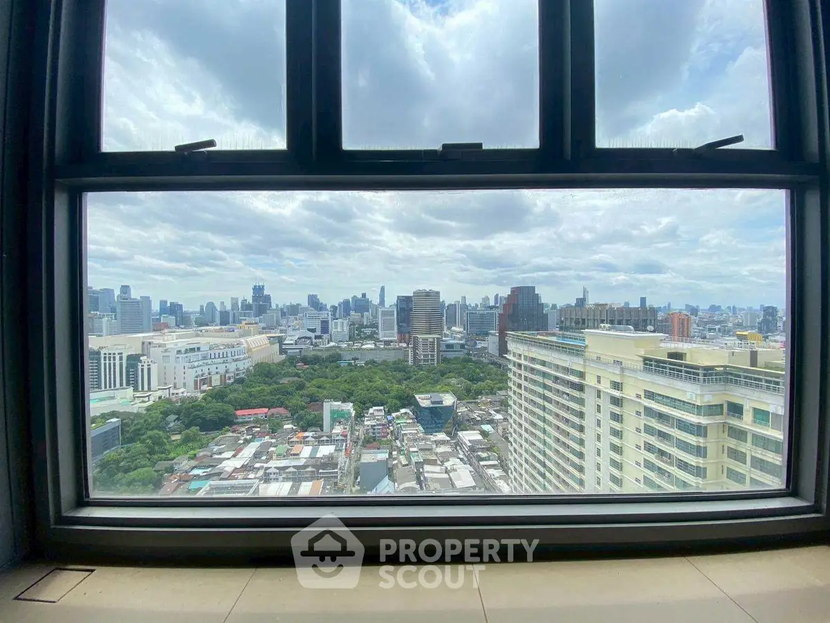 Stunning cityscape view from high-rise window, showcasing urban skyline and greenery.