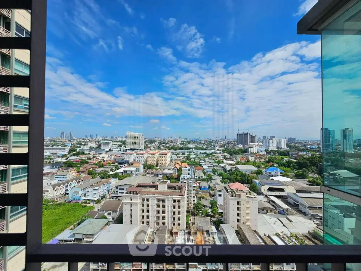 Stunning cityscape view from high-rise balcony with clear blue skies and urban landscape.