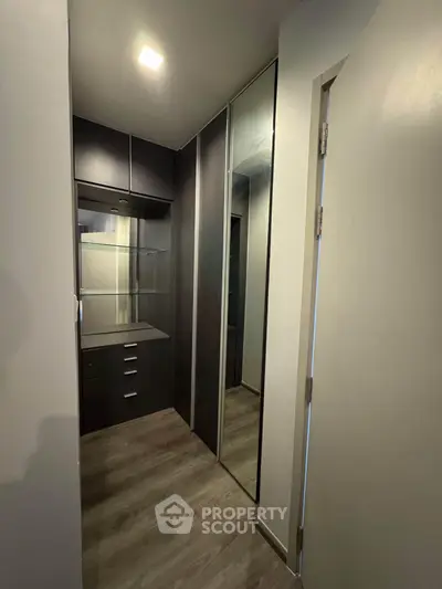Spacious walk-in closet with sleek dark cabinetry and mirrored doors, perfect for modern storage solutions.