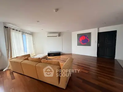 Spacious living room with wooden flooring and modern art, perfect for relaxation.