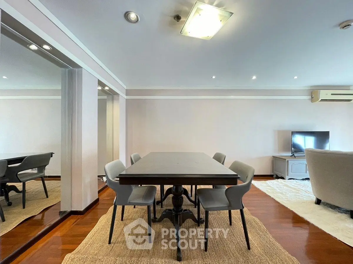 Spacious dining area with elegant table and chairs, featuring polished wooden floors and modern lighting.