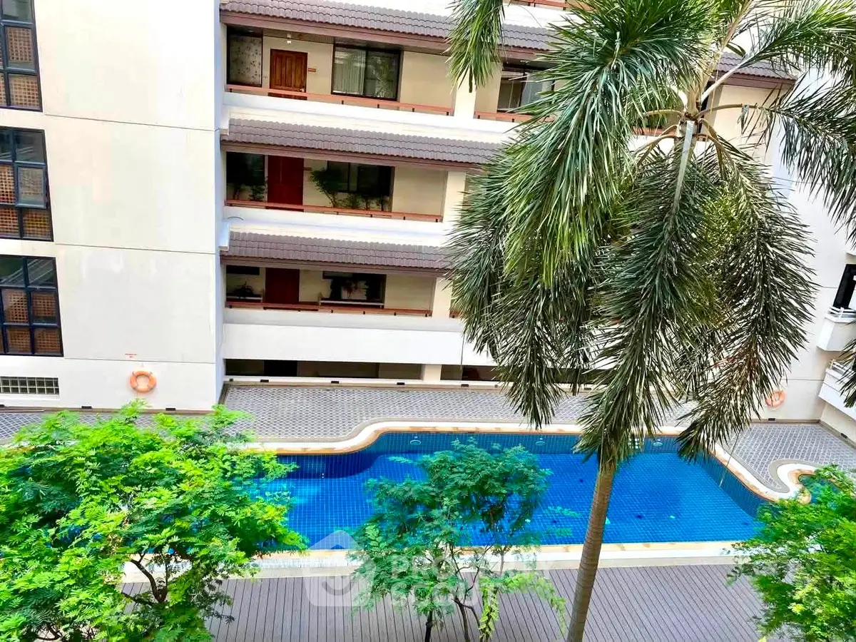 Stunning view of a residential building with a sparkling pool and lush greenery, perfect for relaxation.