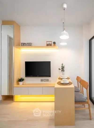 Modern living room with sleek TV setup and stylish dining area in a cozy apartment.