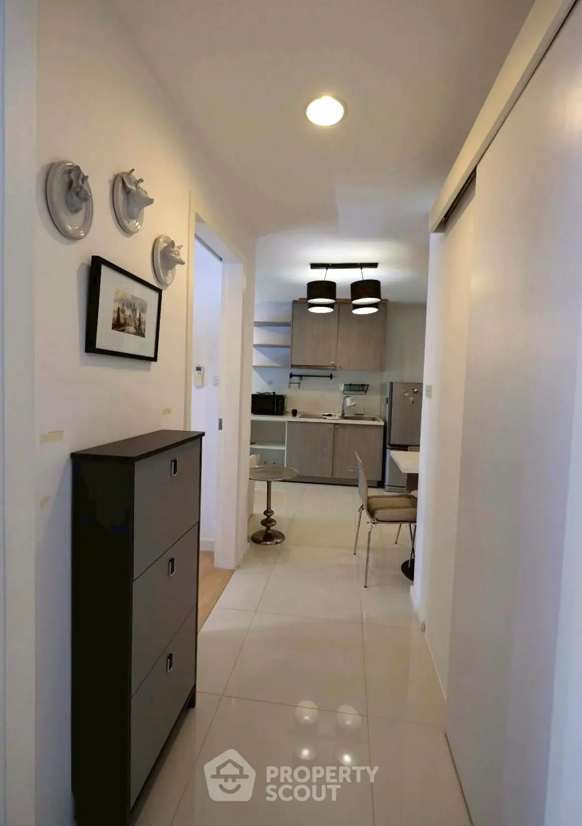 Modern apartment hallway leading to a stylish kitchen with sleek cabinetry and contemporary lighting.