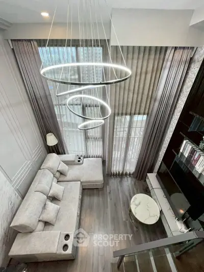 Luxurious high-ceiling living room with modern chandelier and elegant decor