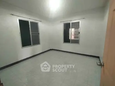 Spacious empty room with tiled flooring and large windows, perfect for customization.