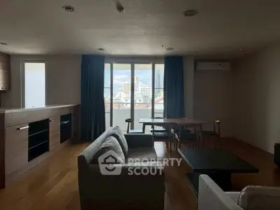 Spacious living room with modern furniture and large windows offering city views.