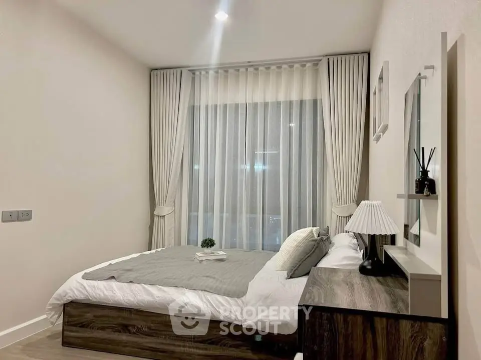 Modern bedroom with elegant decor and large window, featuring stylish curtains and cozy bedding.