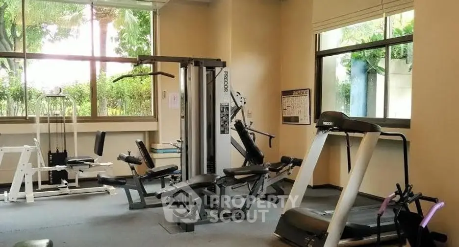 Spacious gym with modern equipment and large windows for natural light.