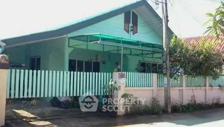 Charming single-story house with green exterior and picket fence