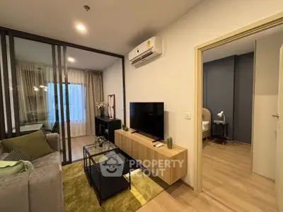 Modern living room with stylish decor and open view to bedroom, featuring sleek furniture and warm lighting.