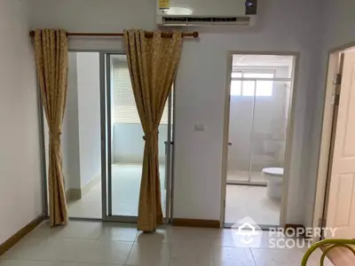 Bright and airy bedroom with sliding glass doors leading to a balcony, featuring an air conditioning unit and an en-suite bathroom.